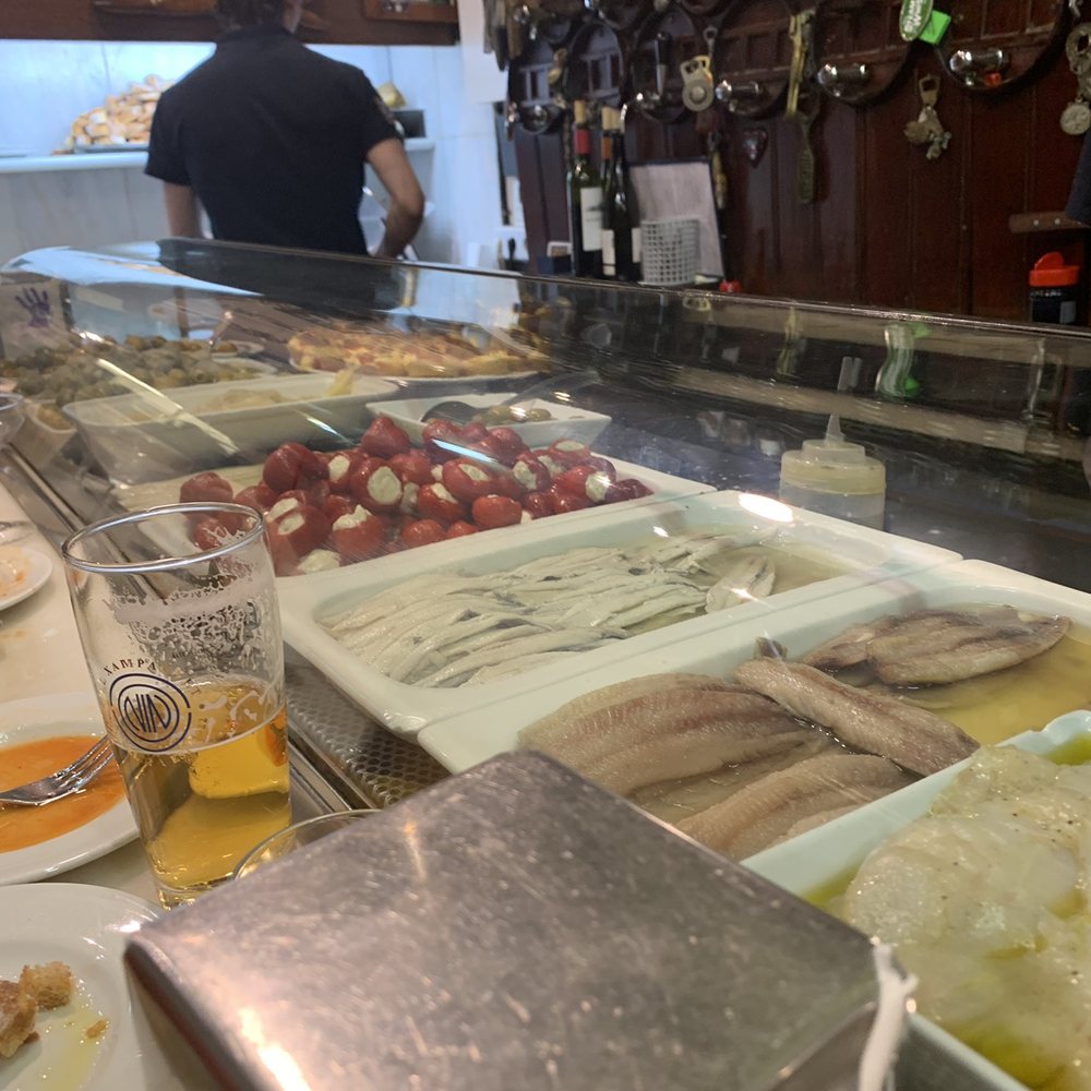 El Xampanyet - Behind the counter, pepedews were a nice bite. You can see the slices of iberico coming off the slicer nice and thin. - Tapas Bars Near Me - Barcelona, B