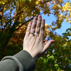 Rohr Jewelers - Hand with engagement ring held up with fall foliage in the background