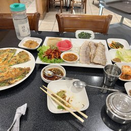 Bossaam and seafood pancake along with side dishes. Bossaam and seafood pancake along with side dishes.