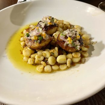 Platea - Scallops on top of Choclo (Peruvian corn) - Seared scallops are topped with a finely chopped onion and pepper mixture, served on a bed of corn, with a yellow sauce around the dish. - Peruvian Near Me - Pinecrest, Florida