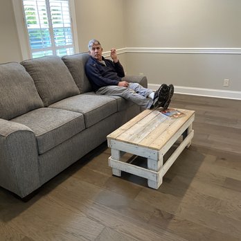 TN Floors - a man sitting on a couch in a living room - Flooring Near Me