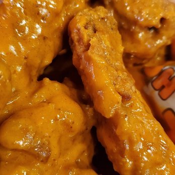 Hooters - Wings were good. - Buffalo chicken wings covered in orange sauce are shown in a close-up view, highlighting their crispy texture and glossy coating. - American Near Me - Albuquerque, New Mexico
