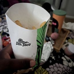 a hand holding a paper cup of fries