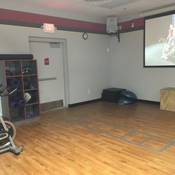 Snap Fitness - Rockford - Group fitness room with storage for personal items, stationary bikes, yoga mats, balance trainer, and Fitness on Demand projector.