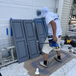 Paintman, LLC - Spraying vinyl shutters first with a bonding primer,sealer, then applying paint