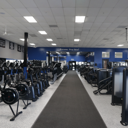 Cardio and strength training area at Epic Health & Fitness Port Richey featuring treadmills, rowers, and free weights in a br...