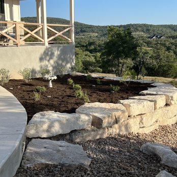 Hill Country Pristine - a patio with a stone wall - Landscaping Near Me Hill Country Pristine - a patio with a stone wall - Landscaping Near Me