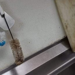 a dirty sink with a toothbrush and cutting board