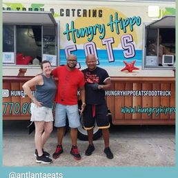 three people standing in front of a food truck