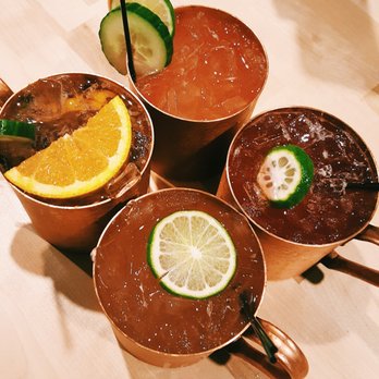The Copper Kettle - (Starting clockwise from the orange slice) The Garden, Cucumber Lime, Pomegranate, and Spiced Pear Moscow Mules. - Bars Near Me - Lincoln, Nebraska