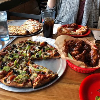 Noon Rock Pizza - a woman sitting at a table with a variety of pizzas - Pizza Near Me - Dubois, Wyoming