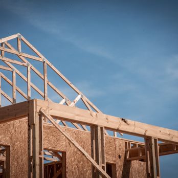 Builders FirstSource - 5. A wooden house frame under construction, featuring exposed beams and plywood walls, is set against a clear blue sky... - Building Supplies Near Me - Idaho Falls, Idaho Builders FirstSource - 5. A wooden house frame under construction, featuring exposed beams and plywood walls, is set against a clear blue sky... - Building Supplies Near Me - Idaho Falls, Idaho