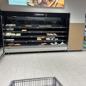 ALDI - All out of chicken (12-27-22 following a big blizzard and Christmas) - Grocery store meat section with empty refrigerated shelves labeled 'POULTRY' and other sections visible, with a shopping cart in the foreground. - Grocery Near Me - Solon, Ohio