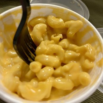 Wing Snob - Mac & Cheese - A plastic cup filled with macaroni and cheese, with a black fork inserted into the pasta. - Chicken Wings Near Me - Monroe, Michigan