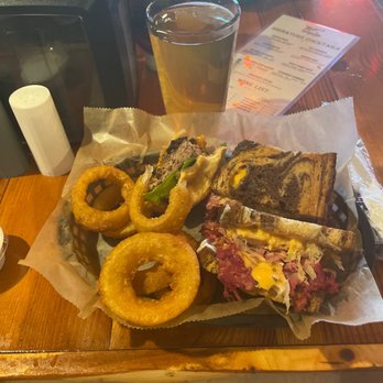 Manci's Antique Club - Reuben and onion rings with Oyster City beer. Special appearance is my fiancé's burger (Manci's burger). We - American Near Me - Daphne, Alabama