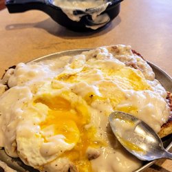 Iron Skillet - Southern tradition: Two giant grilled biscuits fresh pipin hot, sausage gravy two eggs over medium on top