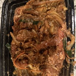 Mushu pork without any cabbage. I was told on the phone that it is cooked into it. Apparently that's a new thing. - A black plastic takeout container contains Mushu pork without cabbage, with shredded pork, vegetables such as carrots and green onions, all coated in a savory sauce. The dish appears moist and is served in a typical takeout presentation, likely from a Chinese-American restaurant offering a variety of dishes including Mongolian beef and orange chicken.