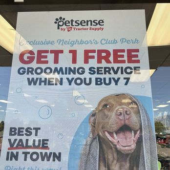 Petsense - Petsense storefront window features a promotional sign offering a free grooming service when buying seven, with a dog image and promotional text. - Pet Groomers Near Me - Rio Rancho, New Mexico