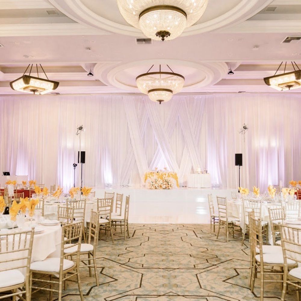 Draping w/ middle section enhancement, seamless white dance floor and wrapped stage, romantic up lights, and gold Chivari chairs.