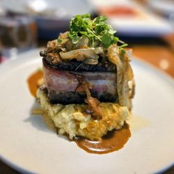 Aurora At The Celeste - BACON WRAPPED ELK "CHOPPED STEAK" (GF) HOUSE SEASONED GROUND ELK | SMOKED NUESKE BACON WILD MUSHROOM | CARAMELIZED ONION | BOURBON SAUCE