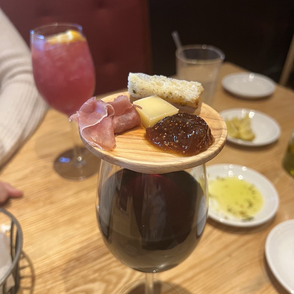 My house wine with small charcuterie on top of the wine glass!