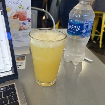 Liquid Provisions - a glass of orange juice next to a bottle of water - Lounges Near Me - Tampa, Florida