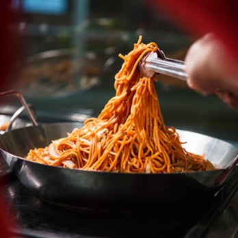 Rice Garden - a person using tongs to stir noodles in a wok - Chinese Near Me - Canutillo, Texas Rice Garden - a person using tongs to stir noodles in a wok - Chinese Near Me - Canutillo, Texas