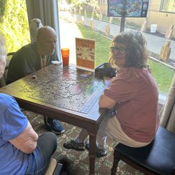 Peach Tree Retirement Center - Two residents and a volunteer are putting a puzzle together, with Chloe, the bird.