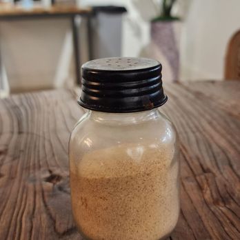 The Doughfellas - a wooden table with a jar of powder - Pizza Near Me - Pompano Beach, Florida