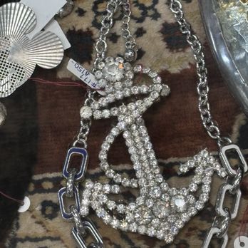 Antiques On Pierce - A large, decorative anchor-shaped necklace covered in rhinestones, attached to a thick chain link necklace. The jewelry is displayed on a patterned surface with other jewelry pieces nearby, including earrings and bracelets. The image appears to be taken at a jewelry or accessory display, possibly at an antique or vintage store. - Antiques Near Me - Milwaukee, Wisconsin