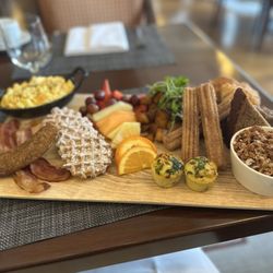 One Eleven At The Capital - Breakfast board: eggs, bacon, sausage, waffles, fruit, potatoes, banana bread, roasted, churros, frittatas, and yogurt w/ fruit & granola