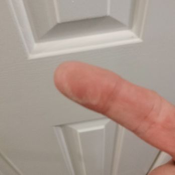 Ana's Cleaning Services - The image shows a finger pointing towards a white door with rectangular raised panels. The door has a decorative molding around the panels and is situated indoors, with a wooden floor visible at the bottom of the frame. The focus is on the finger and the door, with the finger appearing in the foreground and the door in the background. - Home Cleaning Near Me - Durham, North Carolina