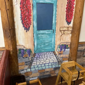 Rutilio's - a table and chairs in front of a painted door - Mexican Near Me - Los Lunas, New Mexico
