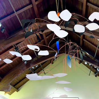Cape Cod Museum of Art - Mobile at Cape Cod art museum - artist was inspired by Alexander Calder - An abstract mobile sculpture with white and black leaf-shaped elements hangs from a wooden ceiling in an art space. - Museums Near Me - Dennis, Massachusetts