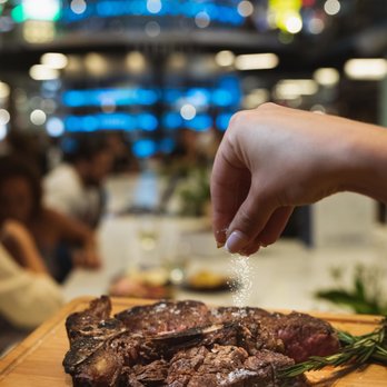 Osso - a person sprinkling salt on a steak - Restaurants Near Me - Miami, Florida Osso - a person sprinkling salt on a steak - Restaurants Near Me - Miami, Florida