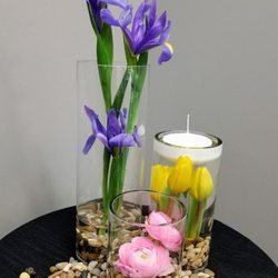 The Fresh Flower & Gift Basket Company - Spring tablescape - Pink Ranunculus, Yellow Tulps underwater, Blue Iris, floating candle and river rocks.