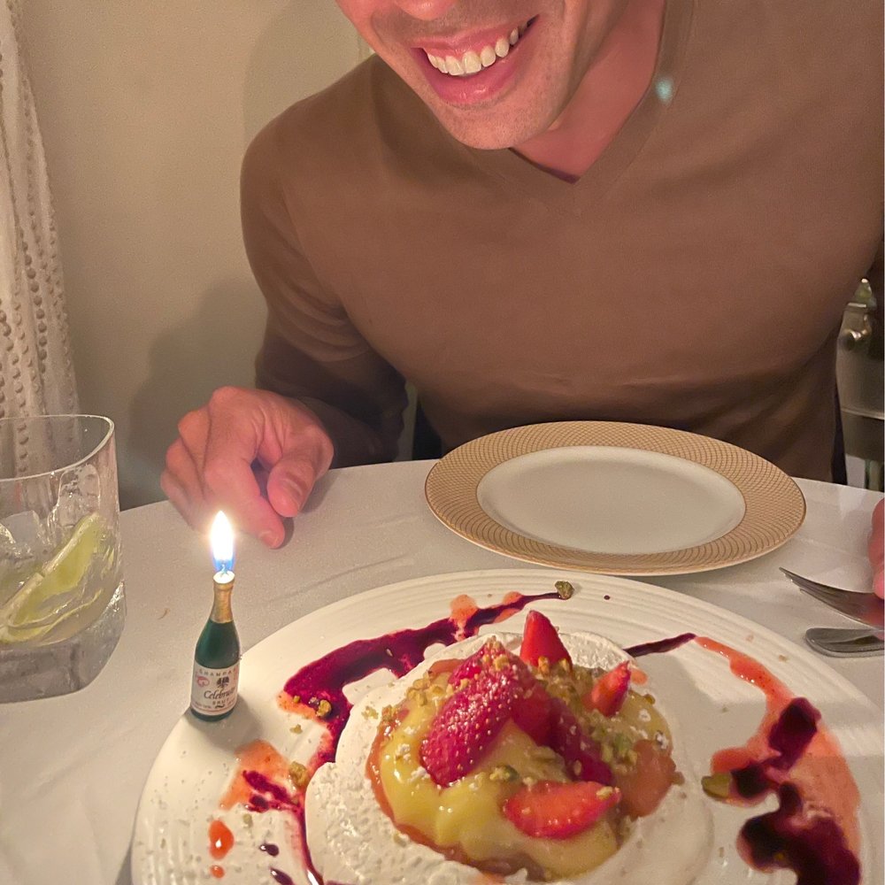 a man sitting at a table with a plate of food and a lit candle