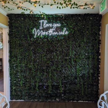 Icing for izaac - a green wall with a neon sign that says i love you more than cake - Bakeries Near Me - Fort Wayne, Indiana