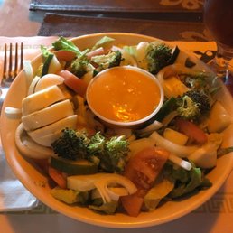 a bowl of salad with a side of dipping sauce a bowl of salad with a side of dipping sauce