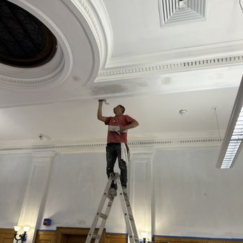 HEW Home Improvement  -  man on a ladder painting a ceiling - General Contractors Near Me