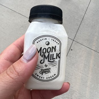 Summer Moon Coffee - Moon milk - A person holds a small, white bottle labeled 'Moon Milk' from Summer Moon Coffee in Austin, Texas, with a black screw cap. - Coffee & Tea Near Me - Bee Cave, Texas
