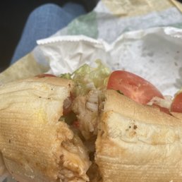 a hand holding a sandwich with meat, tomatoes, and lettuce a hand holding a sandwich with meat, tomatoes, and lettuce