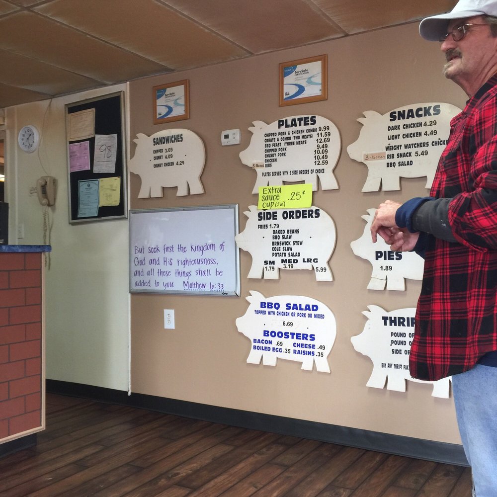 ows a man standing in front of a wall with signs on it ows a man standing in front of a wall with signs on it