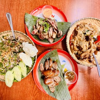 Lao Kitchen - three plates of food on a wooden table - Laotian Near Me - Las Vegas, Nevada Lao Kitchen - three plates of food on a wooden table - Laotian Near Me - Las Vegas, Nevada
