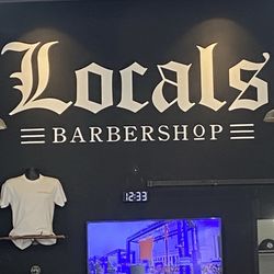 Locals Barbershop - Back wall logo with tv and one of their shirts.