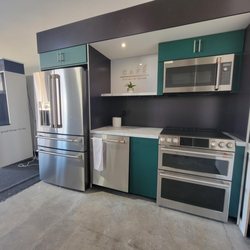 Bray & Scarff - Stainless steel refrigerator, dishwasher, range, and microwave on display with blue cabinets