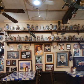 Chef Klaus' Bier Stube - Steins! - The image shows a restaurant interior with a wall adorned with framed photographs and shelves holding numerous beer steins. - German Near Me - Frankfort, Illinois