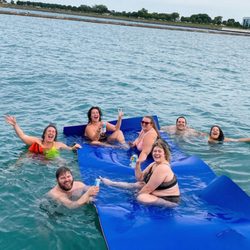Chicago TikiBoat - Book a Chicago Tiki Boat rental and enjoy the water! This photo shows guests using our huge floating mat with drinks in hand on the lake.