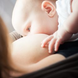Mama Goose Postpartum - White child nursing, mom is in black shrug.