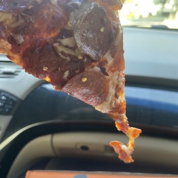 Little Caesars - a slice of pizza being held by a person - Pizza Near Me - Turlock, California Little Caesars - a slice of pizza being held by a person - Pizza Near Me - Turlock, California